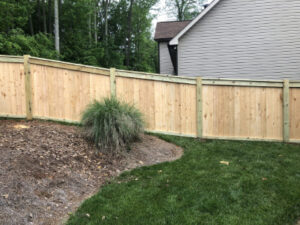 A neatly fenced backyard with green grass and landscaping.