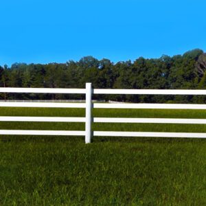 White wooden fence on green grass under a clear blue sky.