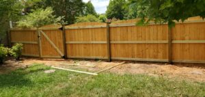 A wooden fence with a small dug-up area in front of it.