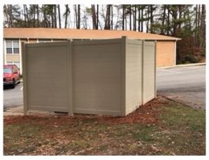 A beige privacy fence enclosing an area near a parking lot.