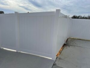 White vinyl fence enclosing a corner of a concrete patio area.