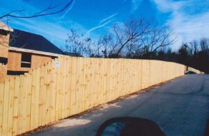 A long wooden fence alongside a road under a clear blue sky.