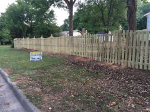 New wooden fence installation along a suburban street.
