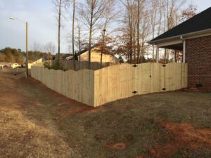 New wooden fence enclosing a backyard with leafless trees.