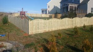 Wooden picket fence enclosing a grassy yard near houses.