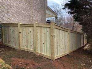 Newly installed wooden privacy fence around a backyard corner.