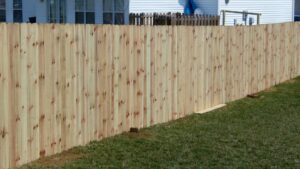 A newly installed wooden fence with a grassy yard beside it.