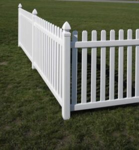 White vinyl picket fence enclosing a grassy area.