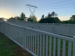 White picket fencing along a suburban pathway with power lines overhead.